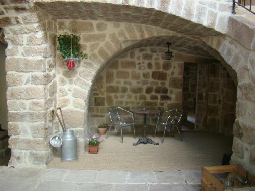 SanilhacChambre Comballe charmante avec jacuzzi的石头墙内带桌椅的庭院