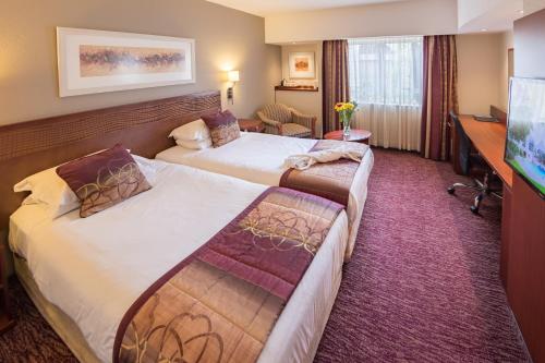 伊丽莎白港City Lodge Hotel Gqeberha的酒店客房配有两张床和一张书桌