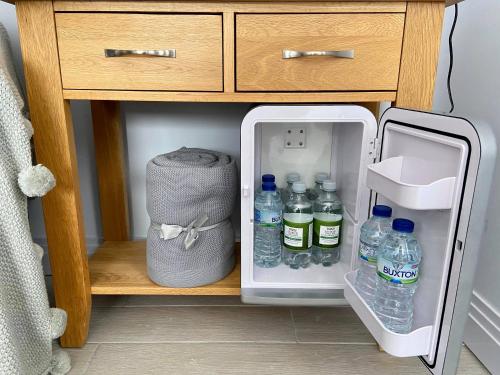 斯托昂泽沃尔德Maugersbury Park Suite的配有瓶装水和袋子的开放式冰箱