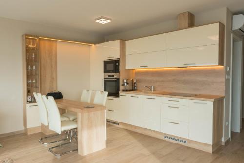 福纽德Heaven's Gate Apartment Fonyód的厨房配有木桌和白色橱柜。