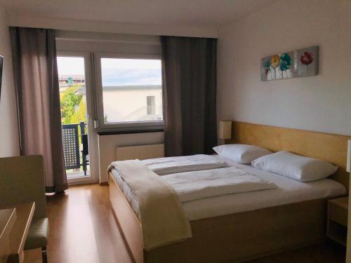 滨湖波德斯多夫潘农思宾馆的一间卧室设有一张床和一个大窗户