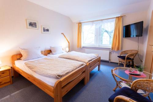 BehringenRhododendronhof的一间卧室设有两张床,墙上配有电视。