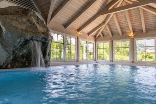 施特罗布尔Bergrose Hideaway的一个带瀑布的游泳池,位于一个设有岩石墙的房间