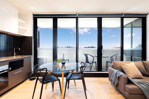 墨尔本Artel Apartments Brunswick的厨房以及带玻璃桌和椅子的客厅。