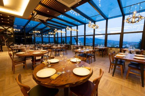 恰纳卡莱Avec Hotel的餐厅设有木桌、椅子和窗户。