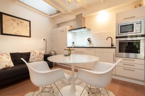 阿尔克马尔CASASdeCASPER - Studio Alkmaar的厨房以及带白色桌椅的起居室。