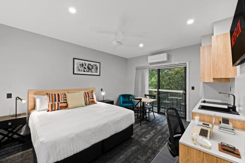 土乌巴AVENUE MOTEL APARTMENTS的酒店客房配有一张床、一张书桌和一间厨房。