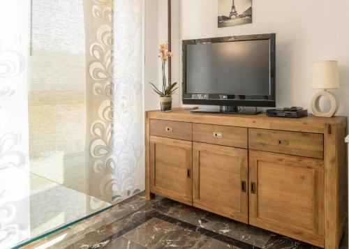 阿尔姆尼卡Lovely studio Cartago的木质梳妆台上方的平面电视