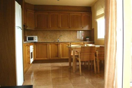 莱斯卡瑟斯-达尔卡纳Apartamento Columbretes的厨房配有木制橱柜和桌椅