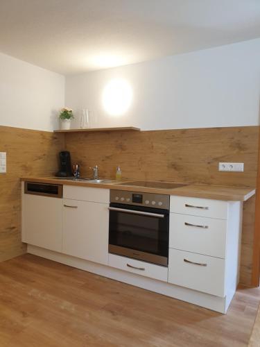 林道HummelHaus 3 in Lindau的厨房配有白色橱柜、水槽和炉灶。