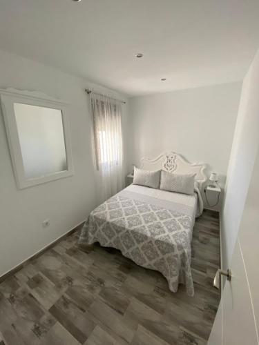 科尼尔-德拉弗龙特拉Conil Apartment的白色卧室配有床和镜子