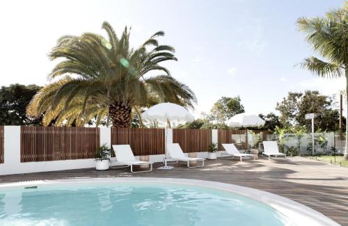 玛志洛Loea Boutique Hotel的一个带白色椅子和棕榈树的游泳池