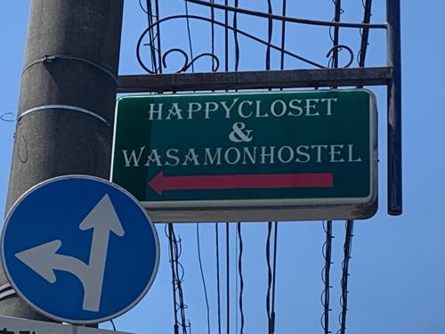 熊本HappyCloset&WasamonHostel的一条绿色的街道标志,在一根杆上,令人高兴,并被围住,