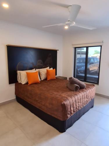 滕南特克里克Safari Lodge Motel的一间卧室配有一张带橙色枕头的大床