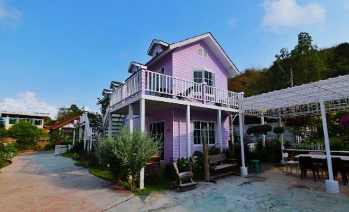 春武里Bunny Hill Resort的粉红色的房子,前面有一张桌子