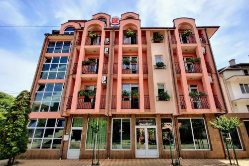 拉夫达Art Villa Rozalia的一座高大的粉红色建筑,阳台上种植了盆栽植物