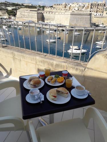 Kalkara波尔图德里奥别墅酒店的一张桌子上的一盘早餐食品,享有海港的景色