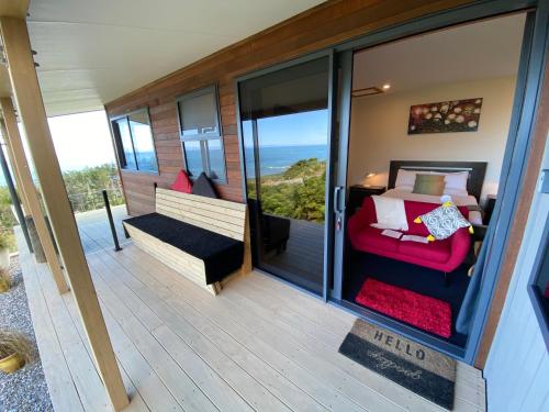 普纳凯基Tasman Sea Retreat的客房设有带一张床和一张沙发的阳台。