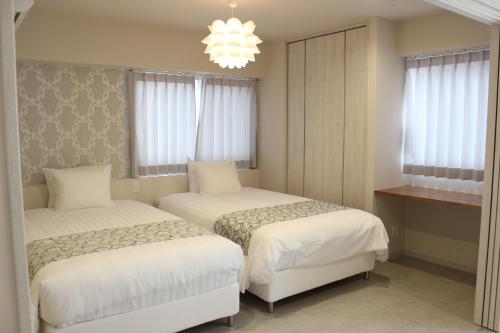 北谷町Hotel Flap Resort的一间卧室配有两张床和吊灯。