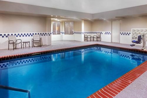 霍普金斯维尔霍普金斯维尔拉昆塔套房酒店 的酒店客房的游泳池配有桌椅