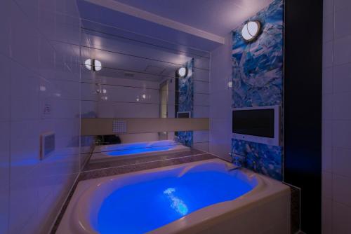 Kami-seyaHotel Eldia Machida -Adult Only的一间带大型蓝色浴缸的浴室,配有电视