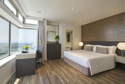 新加坡新加坡宾乐雅服务公寓的配有一张床、一张书桌和一扇窗户的酒店客房