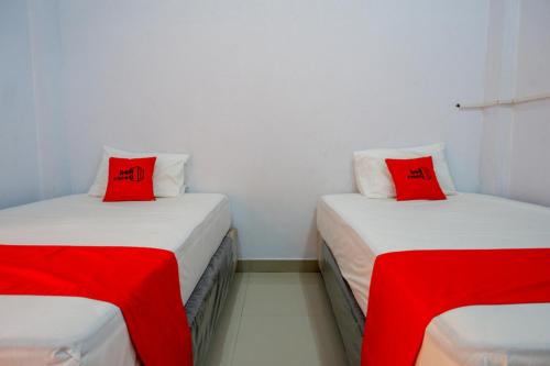 兰特包RedDoorz At Rantepao Toraja Utara的宿舍间内的两张床,配有红色枕头