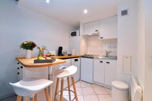 科尔马Appartement La Terrasse sur cour的厨房配有白色橱柜、桌子和凳子