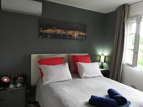 帕特里莫尼奥Chambre d'hôtes à 5mn des plages的一间卧室配有红色和白色枕头的床