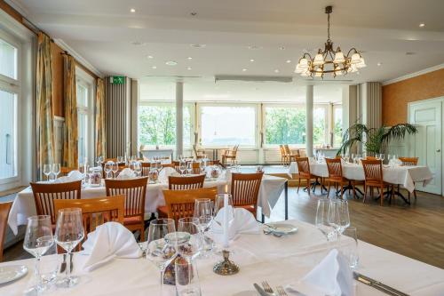 图恩Schönbühl Hotel & Restaurant Lake Thun的餐厅配有白色的桌椅和吊灯