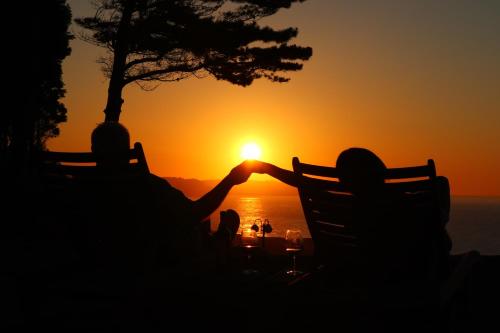 卡拉维亚Casa Particular的两个人坐在长凳上看日落