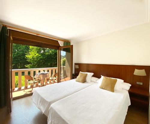 巴约讷安特雷里罗伯斯酒店的带阳台的酒店客房内的两张床