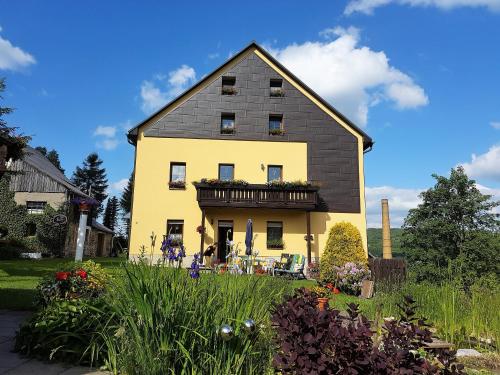 奥泊维森塔尔Ferienwohnungen "Am Schlössel"的黑色屋顶的大型黄色房屋