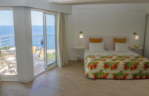 丰沙尔Florasol Residence Hotel - Dorisol hotels的一间卧室设有一张床和一个海景阳台