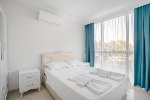 迪迪姆Antioch Apart Otel的一间卧室配有白色的床、蓝色窗帘和窗户