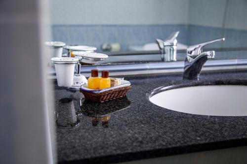 奇维塔卡斯泰拉纳艾尔德罗酒店的一个带水槽的浴室台面和一篮子的瓶子