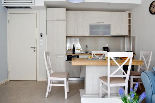 蒂瓦特Ralux apartman Tivat的厨房配有白色橱柜和桌椅