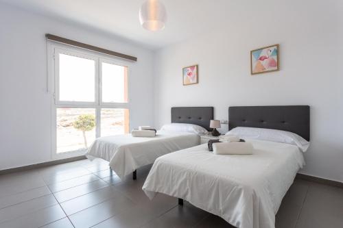 罗萨里奥港Mariposas Home Pool的白色客房的两张床,设有窗户