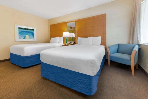 劳德代尔堡La Quinta by Wyndham Fort Lauderdale Pompano Beach的酒店客房,配有两张床和椅子