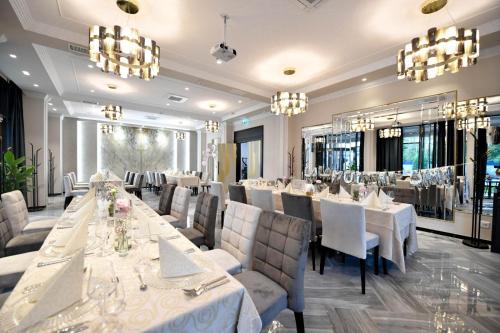 蒂米什瓦拉Pensiunea Nora Prestige的餐厅设有白色的桌椅和吊灯。