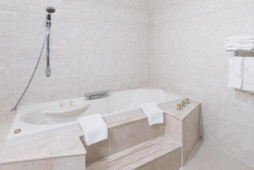 希克斯维尔希克斯维尔戴斯酒店-长岛的白色的浴室设有浴缸和水槽。