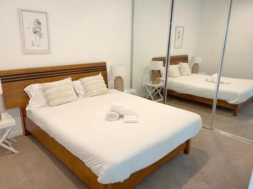 布里斯班Perfect short term stay in Brissy Cozy & Relax的一间卧室配有两张带白色床单和镜子的床