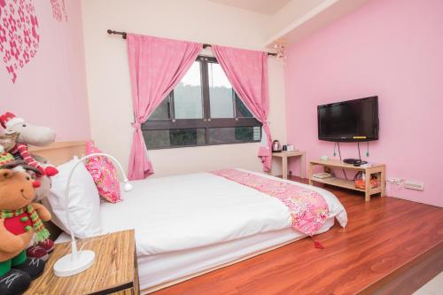 三义甘丹民宿-三義火車站前的粉红色的卧室配有床和电视