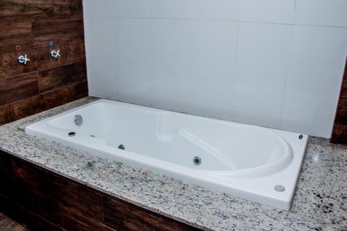 马拉巴INACIO'S PLAZA HOTEL的浴室内一个位于柜台上的白色浴缸