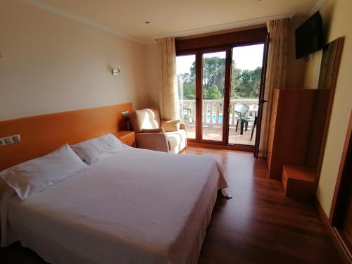 格罗韦Apartamentos Ay Sálvora的卧室配有白色的床和滑动玻璃门
