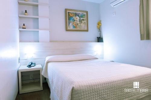 坎普莫朗Hotel Santa Maria的卧室配有白色的床、桌子和书架
