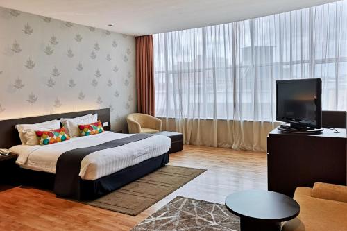 古晋古晋菩提树酒店的一间卧室配有一张床、一台电视和一张沙发