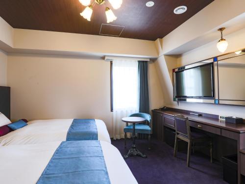 东京Hotel Wing International Select Ikebukuro的酒店客房配有一张床、一张书桌和一台电视。