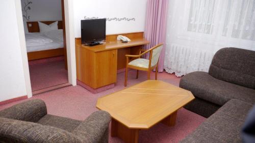 奥伊宾Naturparkhotel Haus Hubertus的酒店客房配有带电视和椅子的书桌