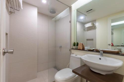 马尼拉Selah Garden Hotel Manila的一间带水槽、卫生间和镜子的浴室